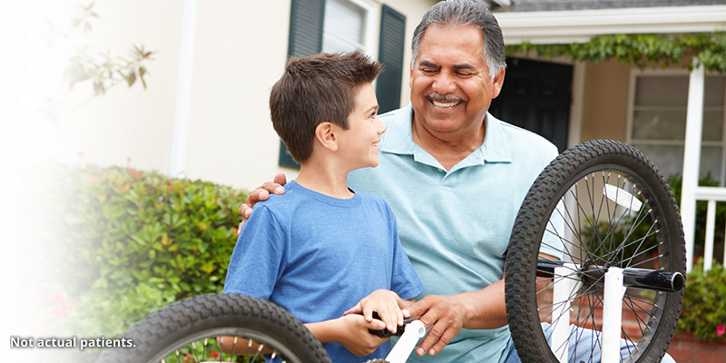 Older man working on a bike wheel with a young boy.