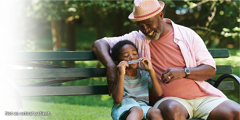 Man with a young boy playing the harmonica.